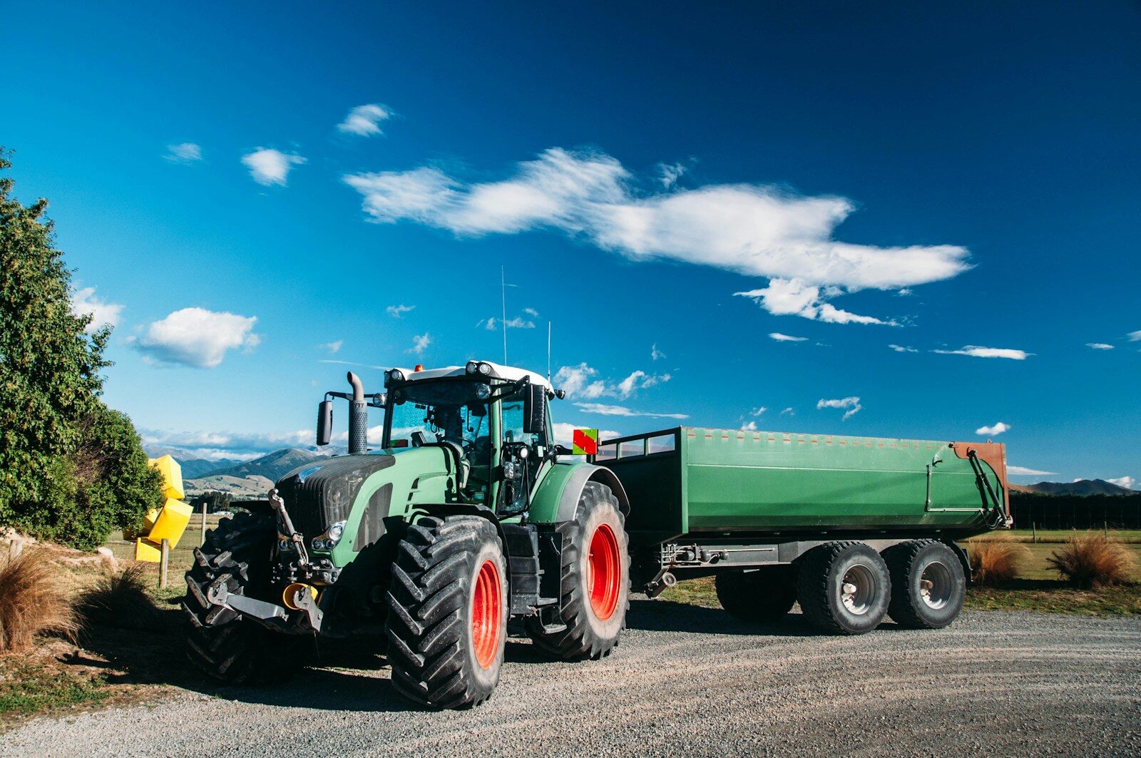 A large green truck driving down a rural road